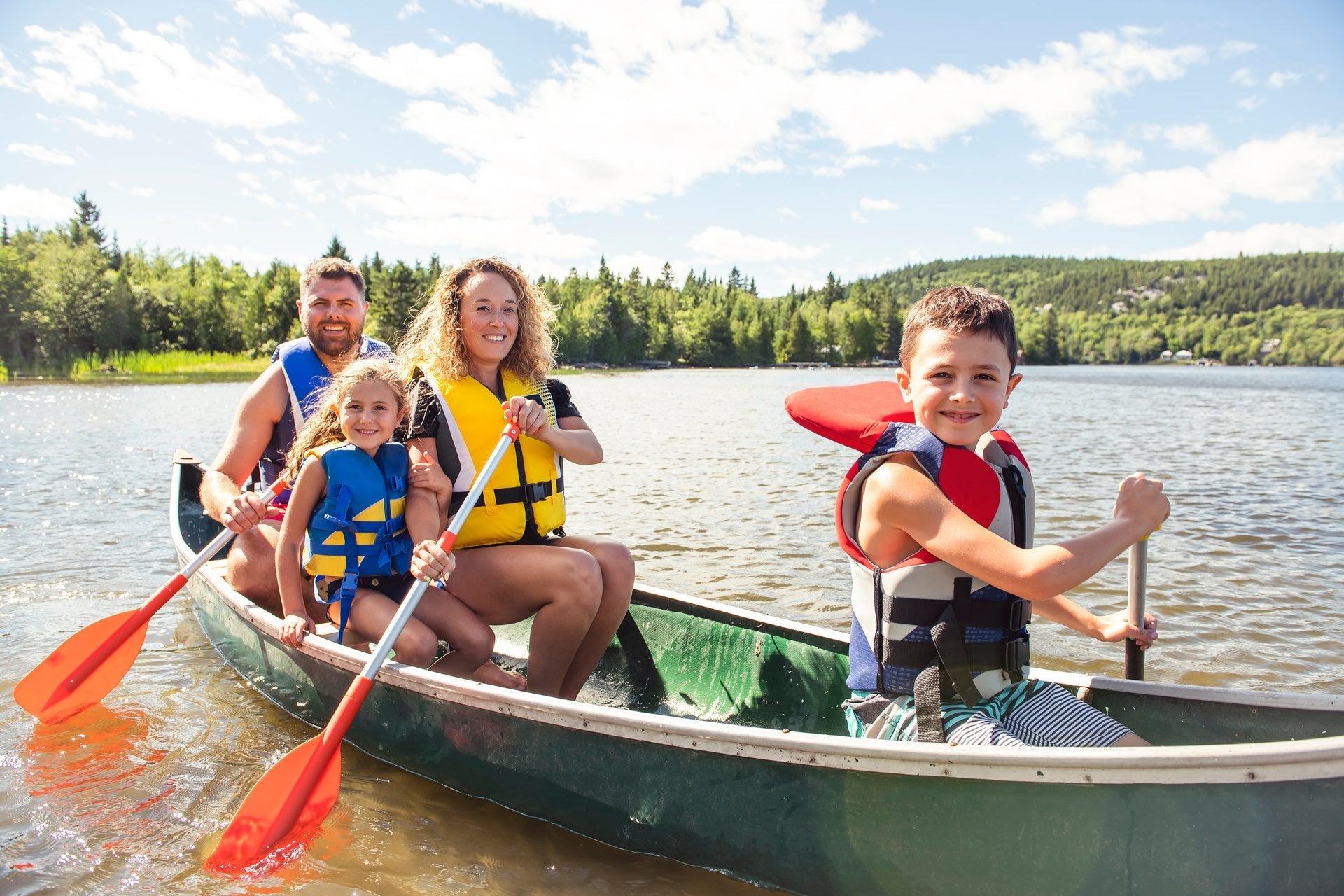 Family in a Canoe wearing life jackets on a Lake having fun