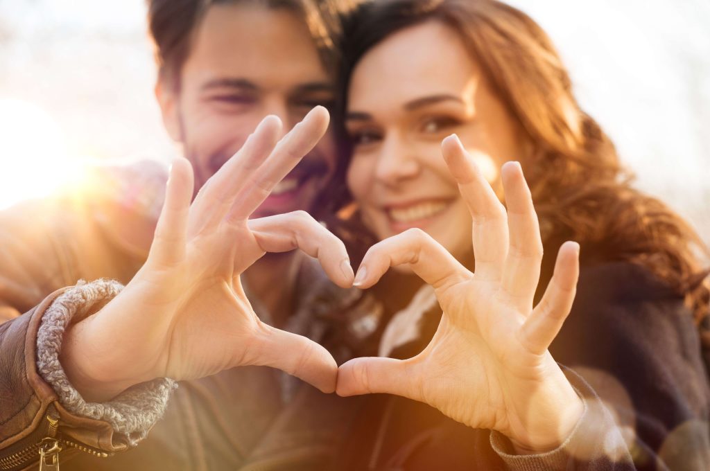 Man and woman making a heart symbol together