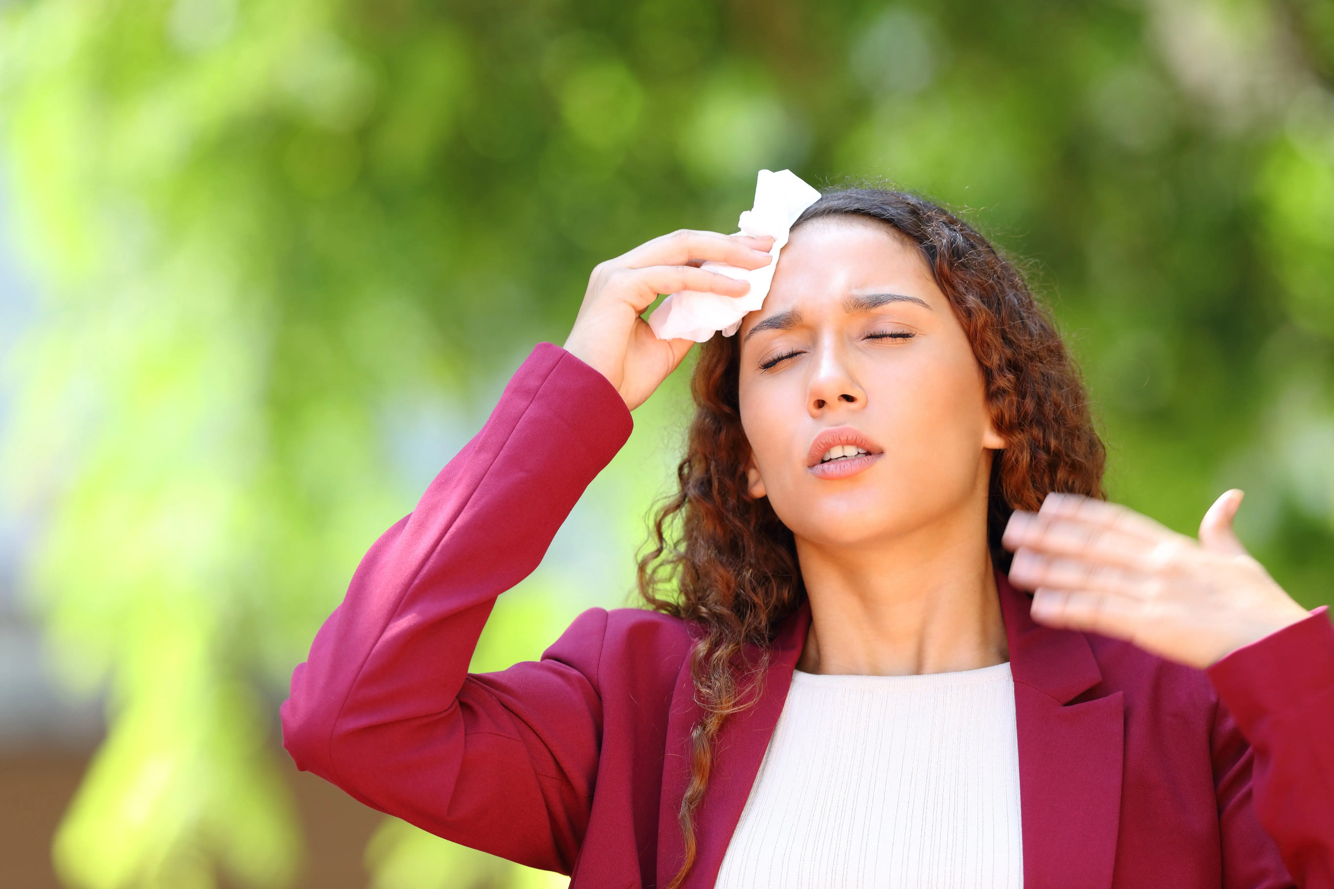 Woman outdoors feeling dehydrated, dizzy, and a headache.