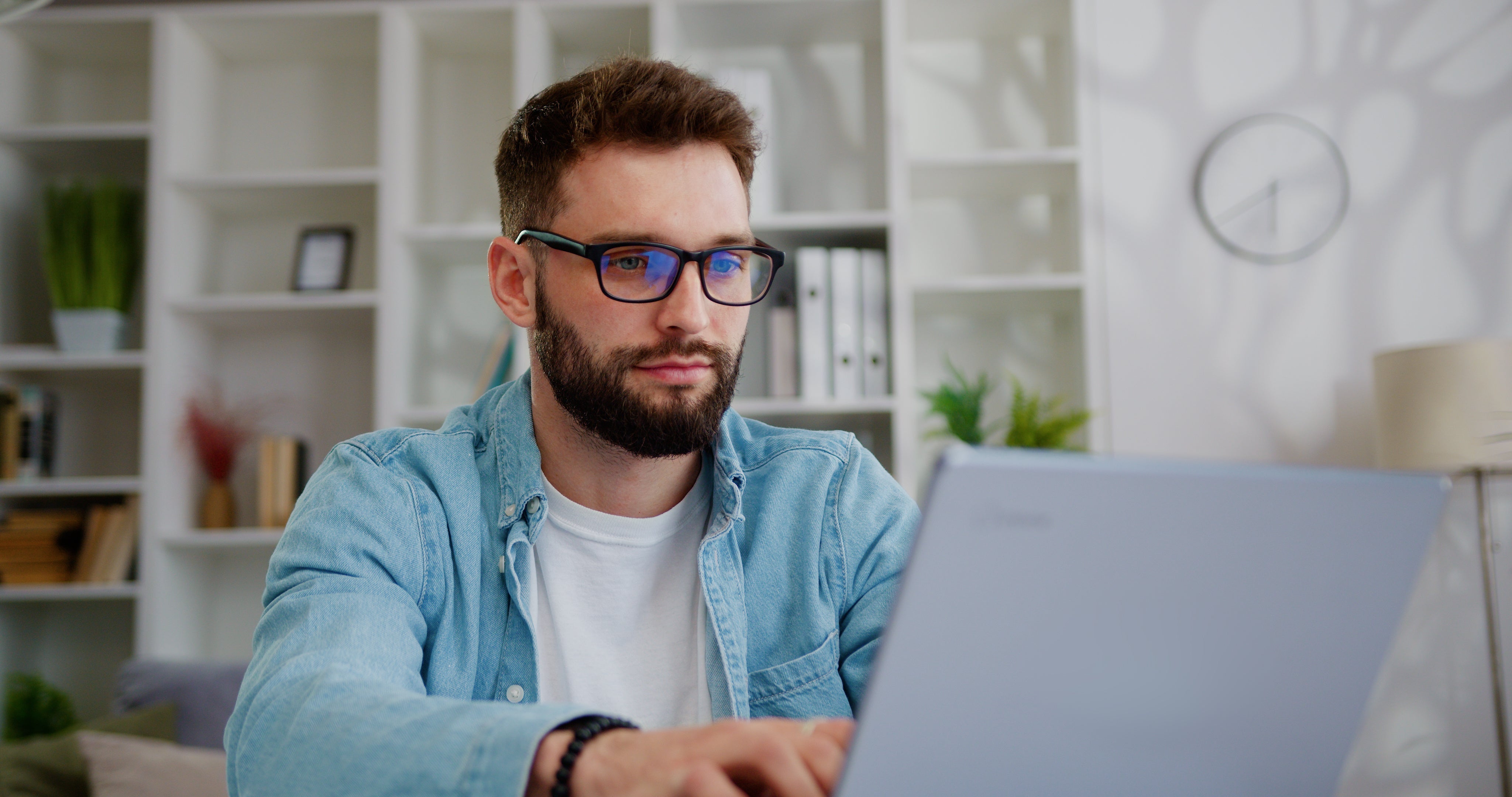 Young bearded man sitting at desk working on computer.