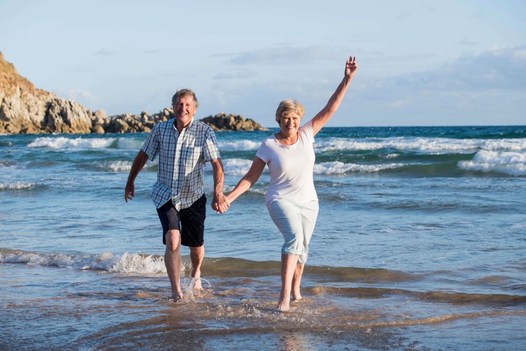 Lovely mature couple walking happy and relaxed on beach sea shore in healthy aging together