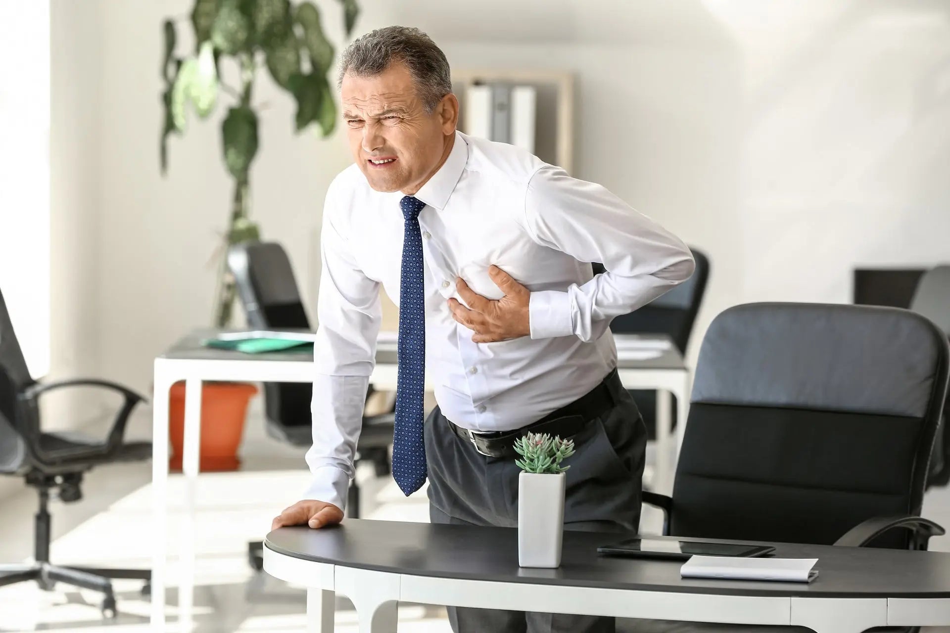 Man suffering from chest pain his office at work, seed oil heart damage concept