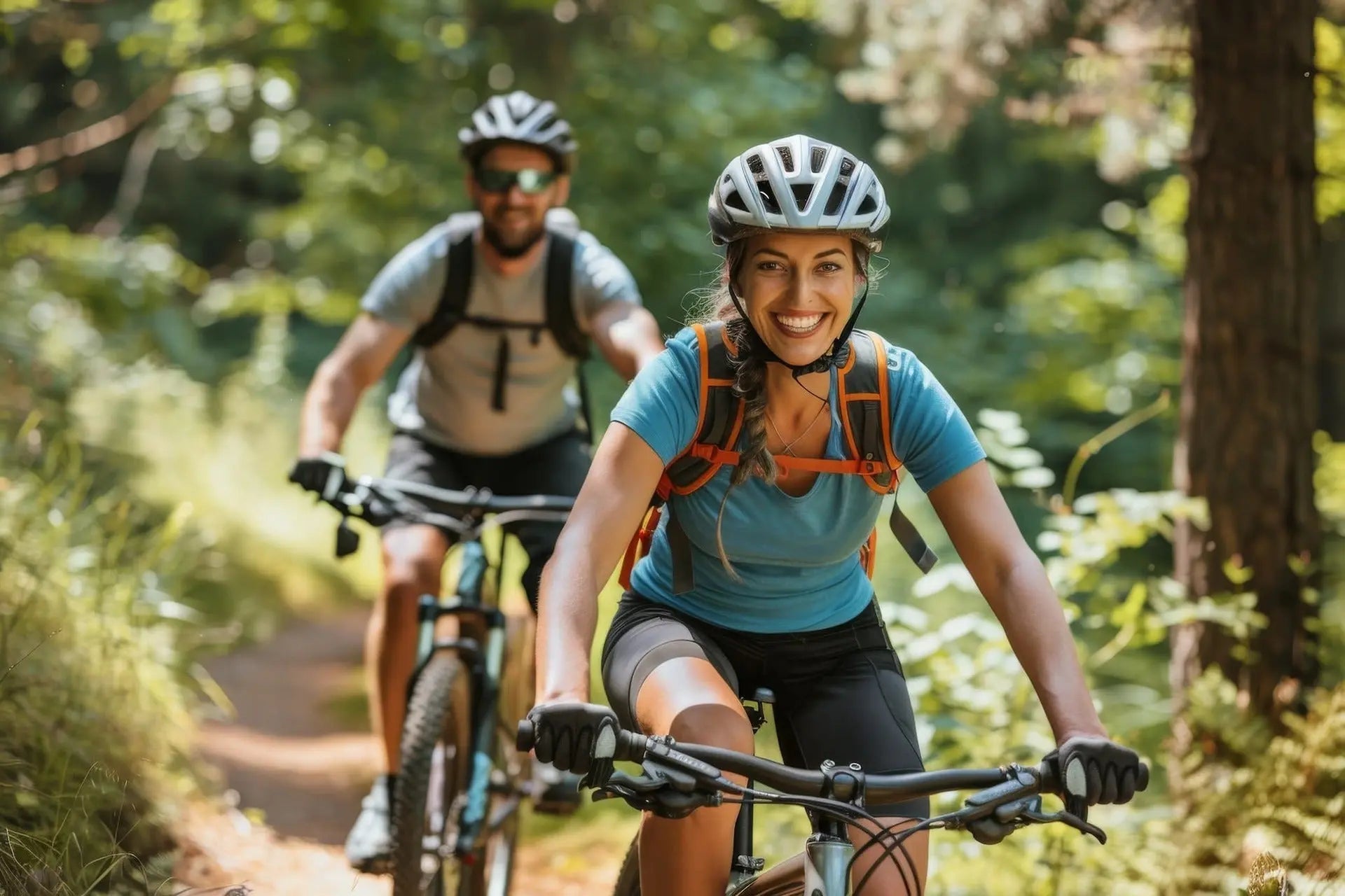 A joyful couple rides mountain bikes together on a sunny forest trail